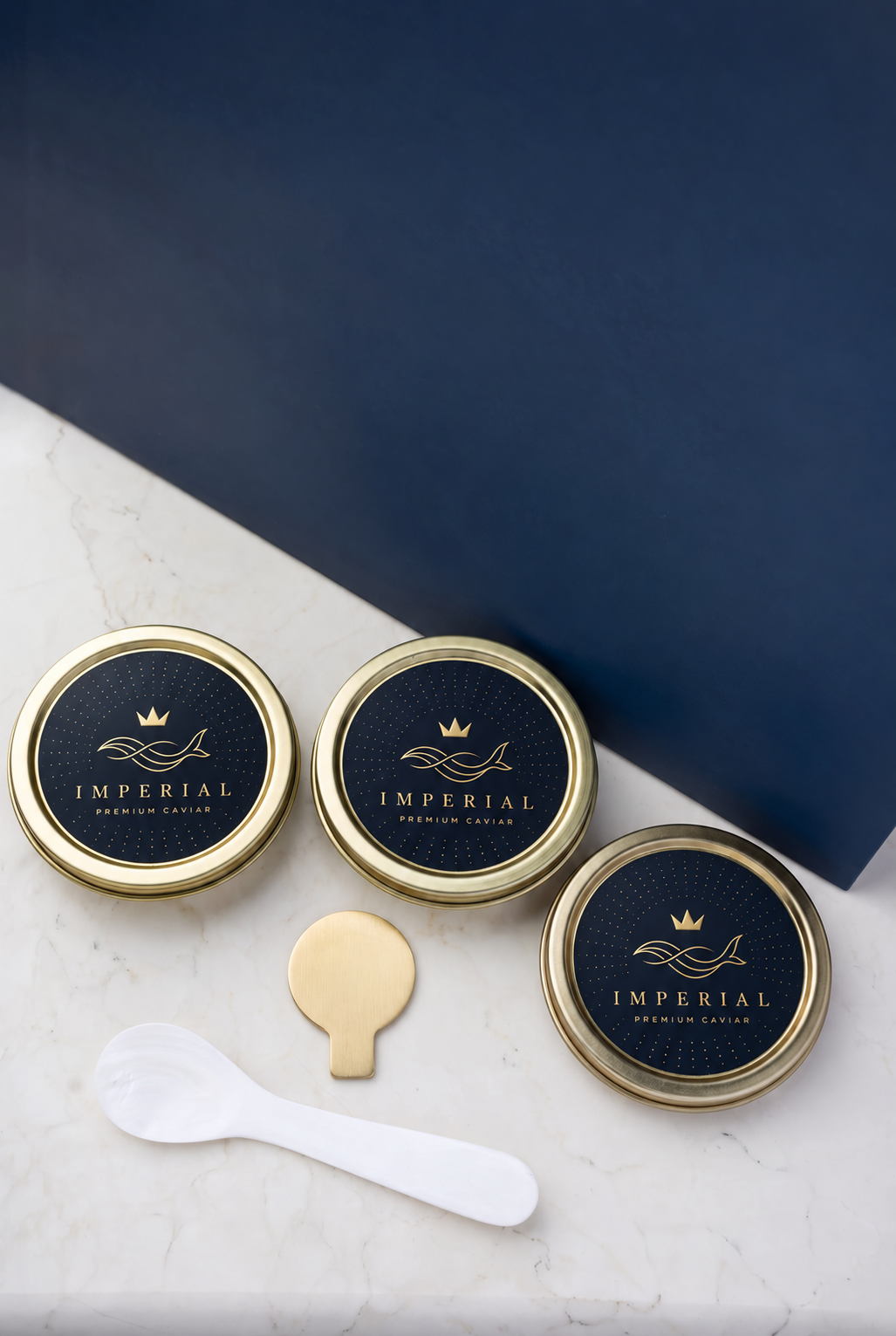 Tre Imperial Premium Caviar-burkar med guldlock, pärlemorsked och burköppnare på marmor